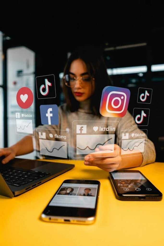 A young woman working on a laptop with holographic social media icons and data analytics charts floating in front of her.